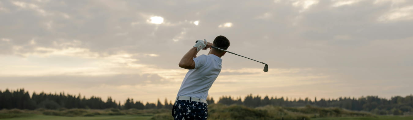 Male golfer in mid-swing on a golf course at sunset, symbolizing elite athletic performance and global ambition – banner image for Hogan Lovells and GSE Worldwide case study
